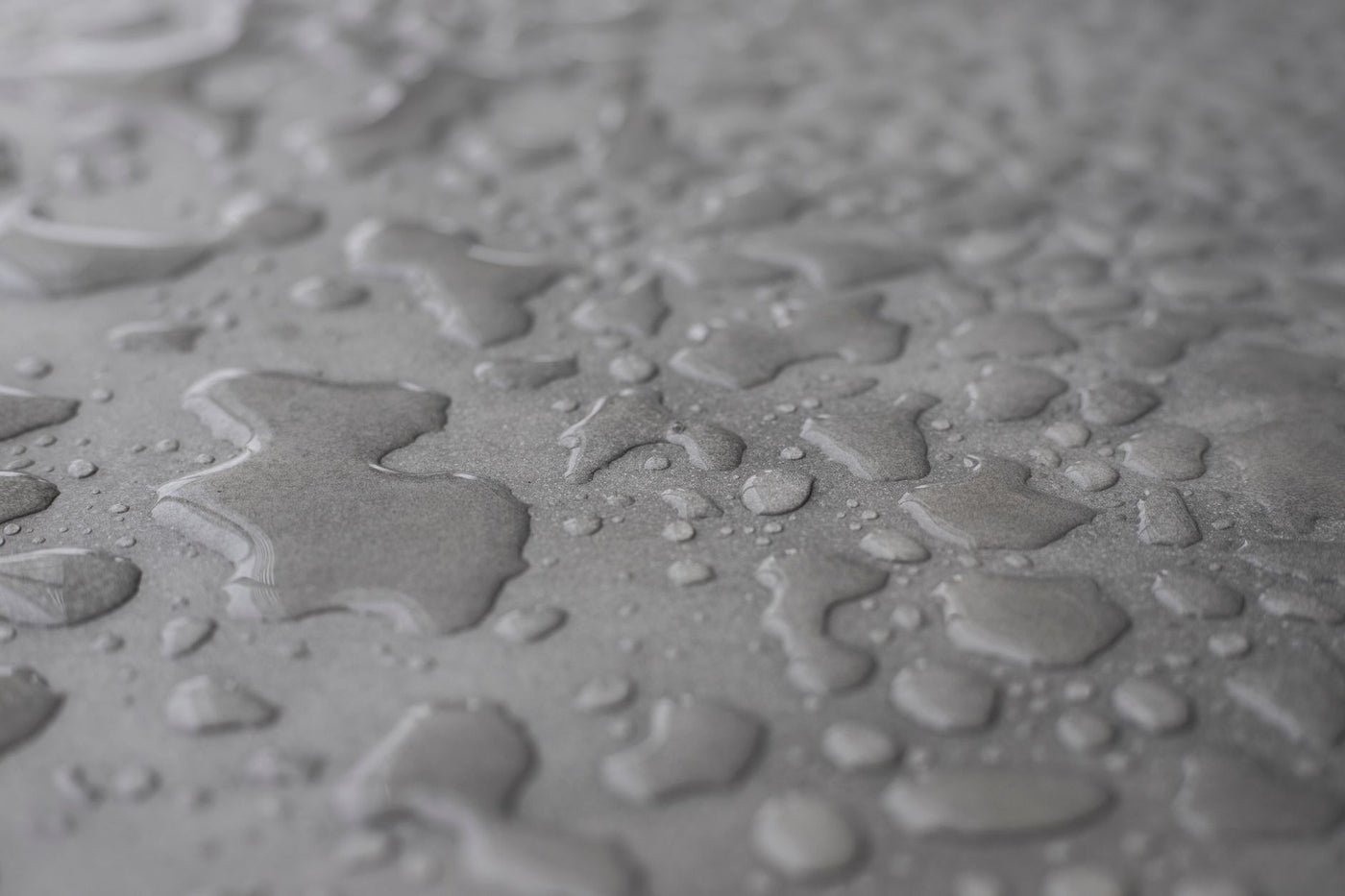 Detailed shot of water drops on a light grey surface with soft focus.