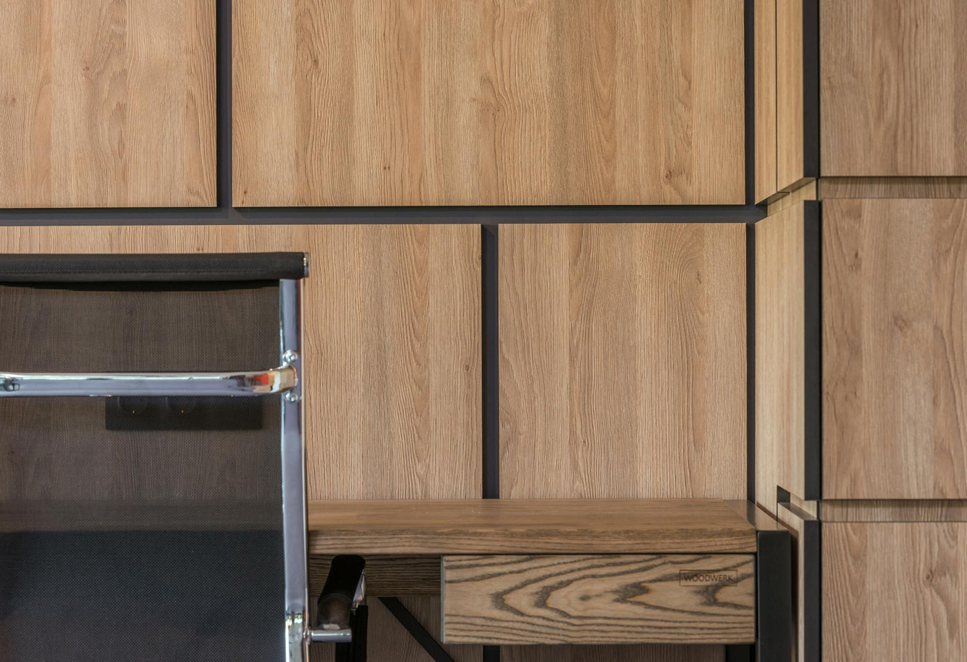 Comfortable chair placed at desk near large wooden cabinet in working room of modern apartment